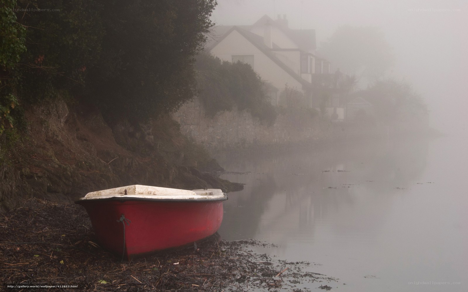Red boat on misty riverbank