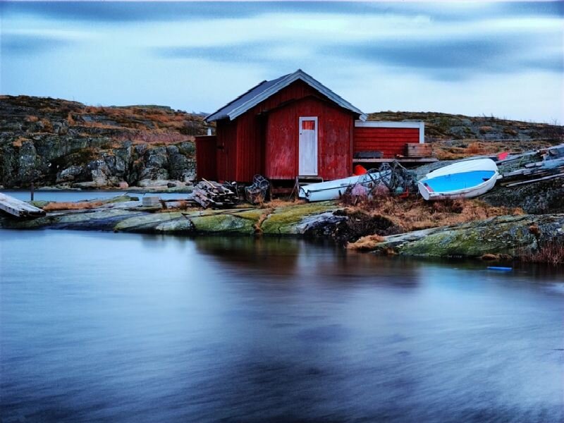 Red boathouse on rocky shore
