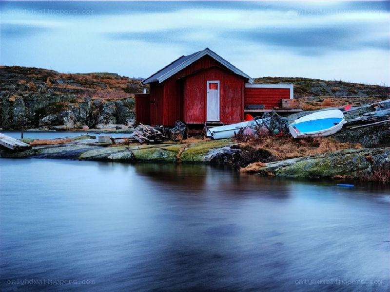 Red boathouse on rocky shore