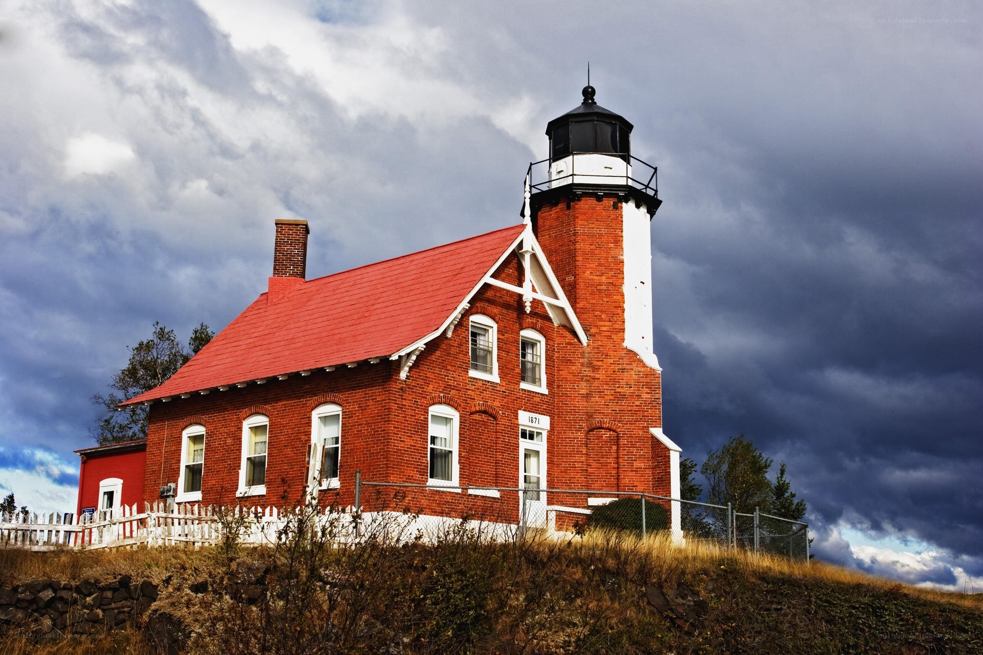 Red brick lighthouse under stormy sky