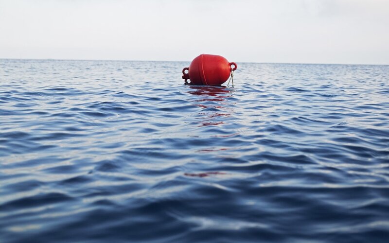 Red buoy floating on calm sea