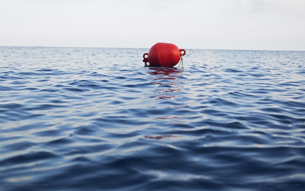 Red buoy floating on calm sea