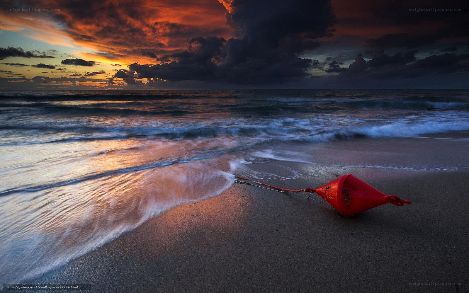 Red buoy on beach at sunset