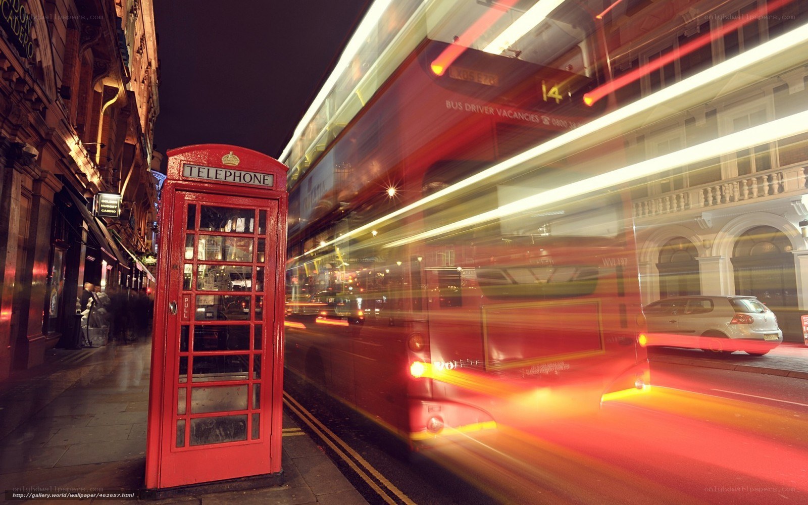 Red bus and phone booth at night