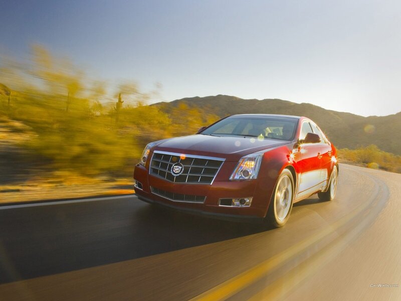 Red Cadillac driving on a road