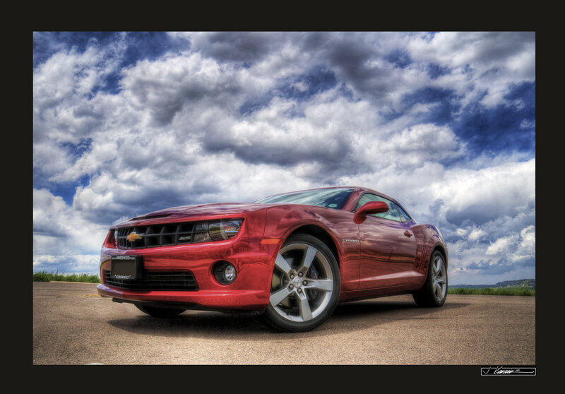 Red Camaro under cloudy sky