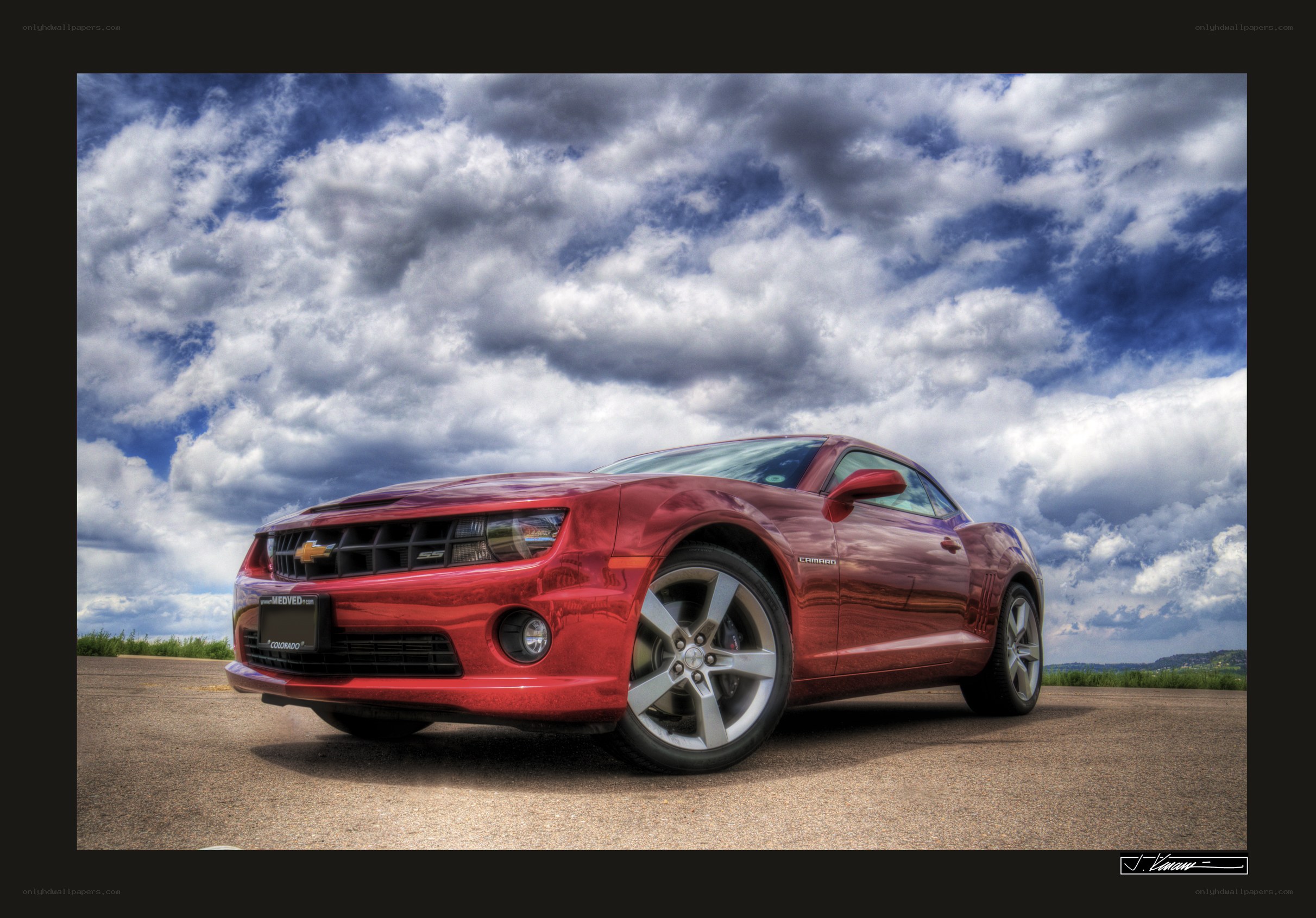 Red Camaro under cloudy sky