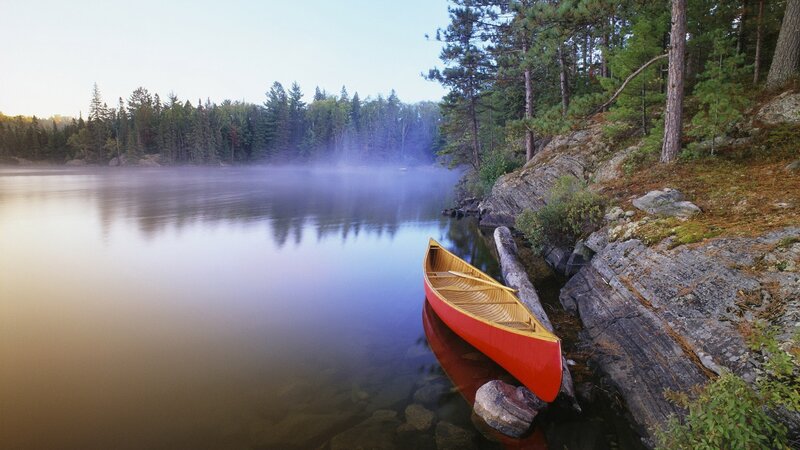 Red canoe on misty lake shore