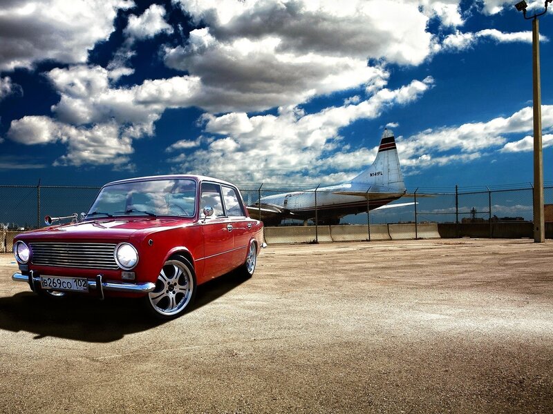 Red car and airplane at airfield