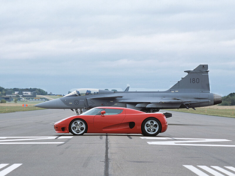 Red car and fighter jet on tarmac