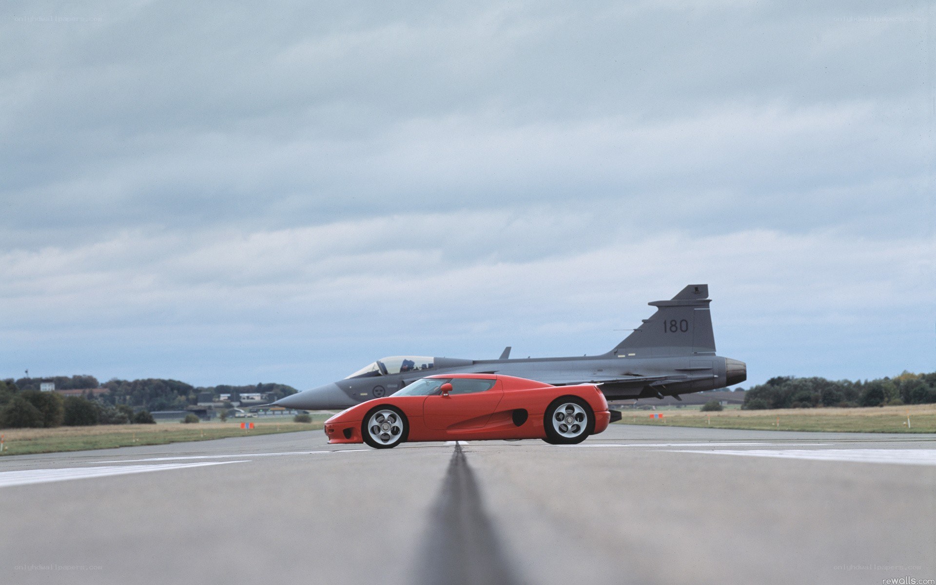 Red car and jet on runway