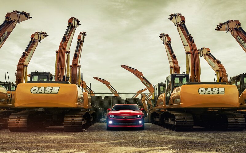 Red Car Between Excavators — Orange, Dramatic
