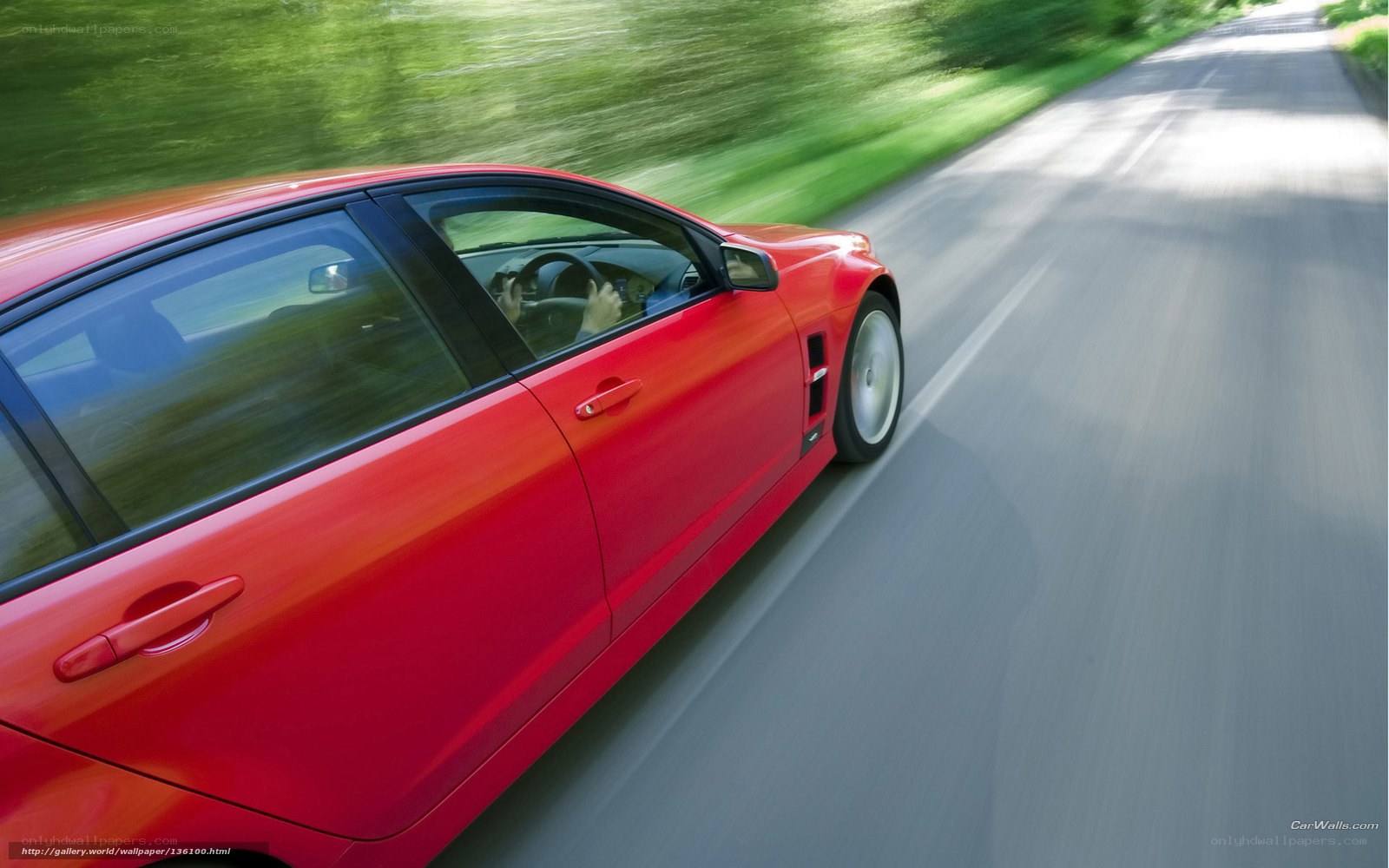 Red car driving on country road