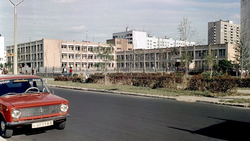 Red car in front of a Soviet-era building