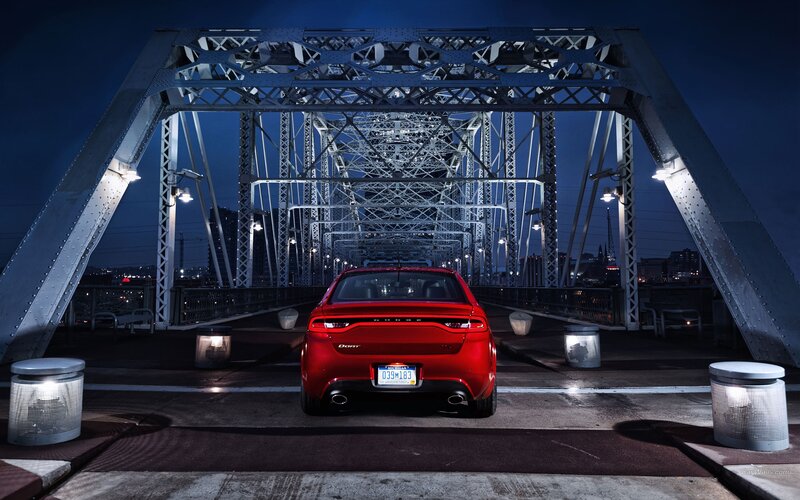 Red car on a bridge at night