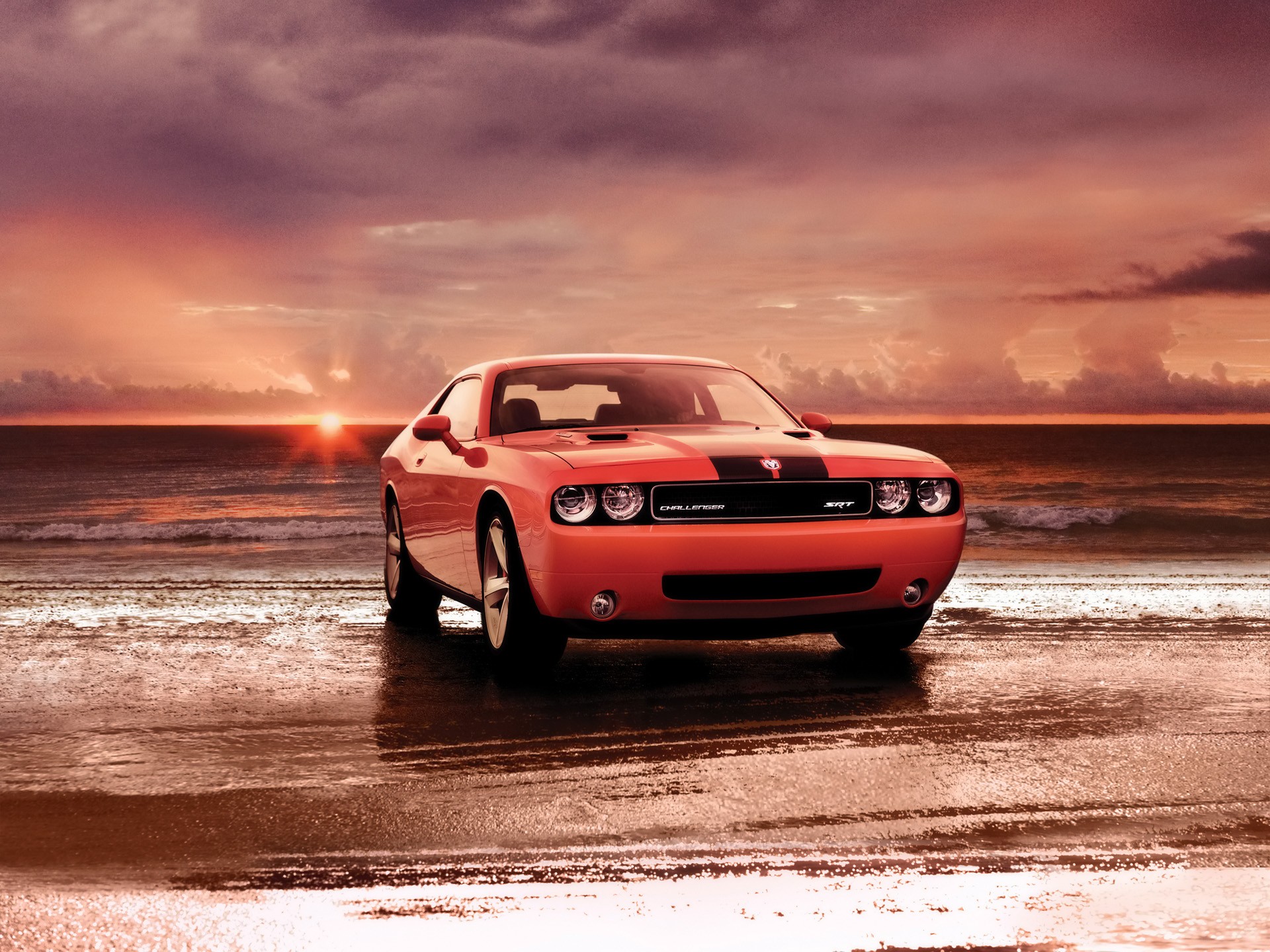 Red car on beach at sunset