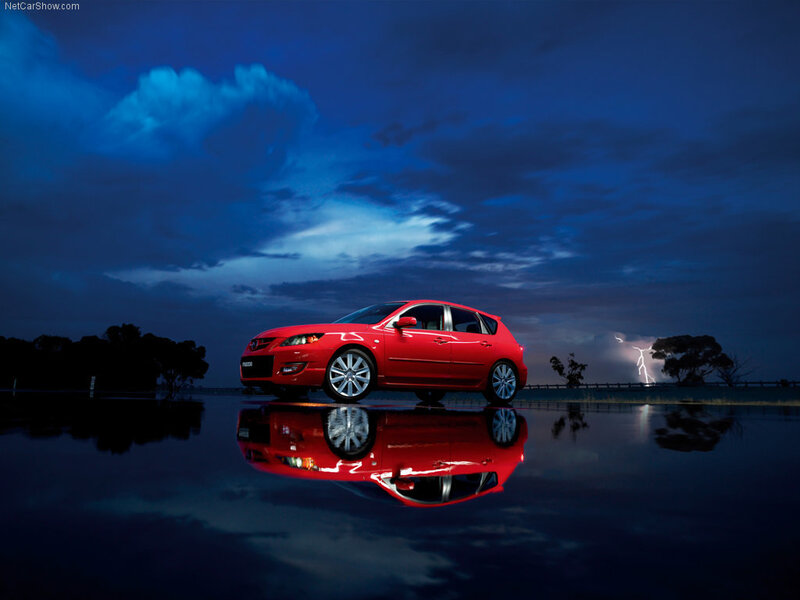 Red car on wet road at night