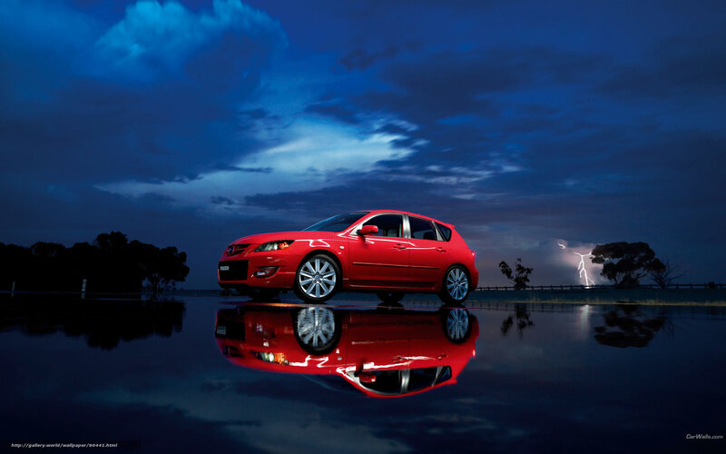 Red car on wet road at night