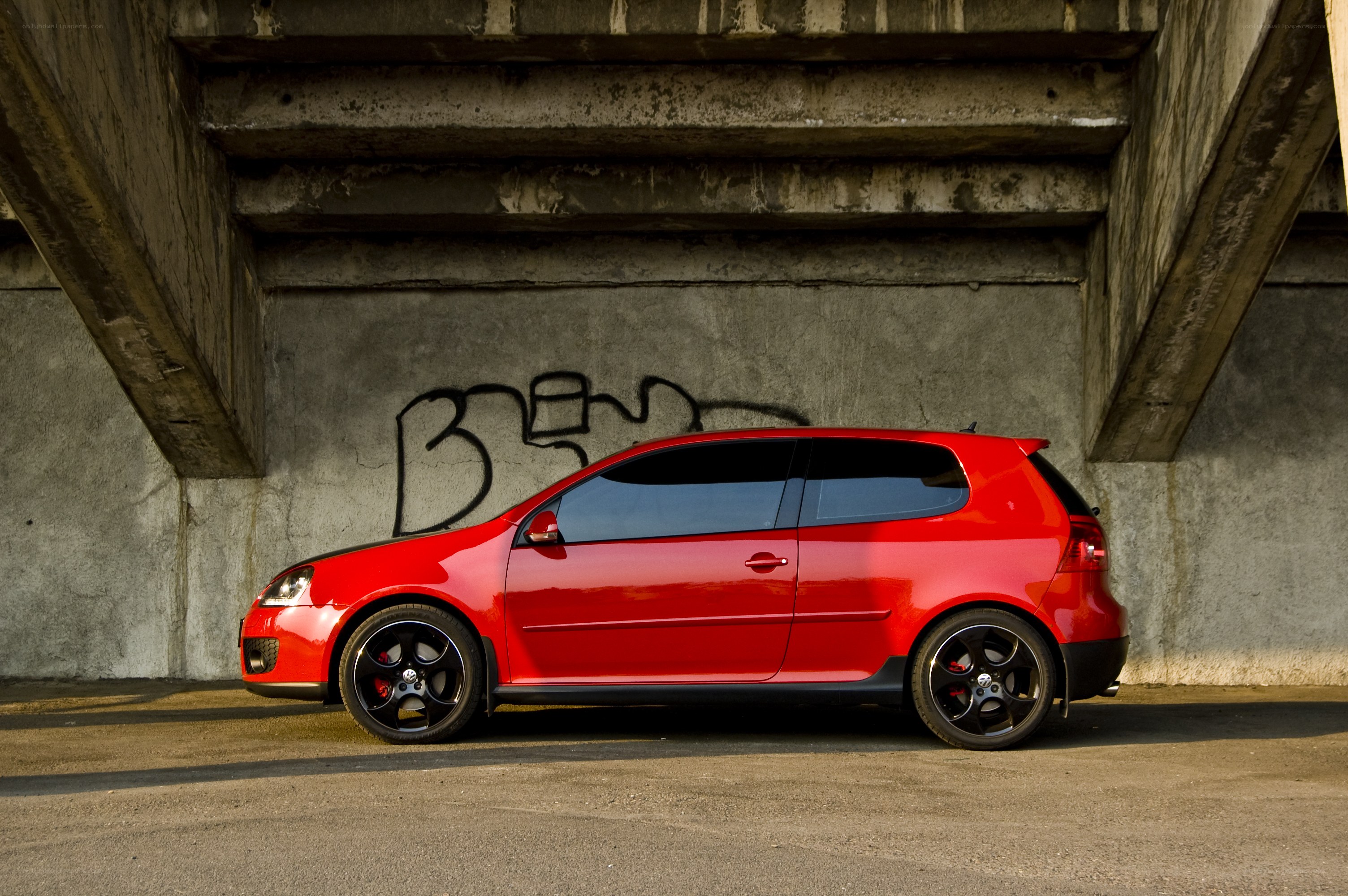 Red car under concrete bridge