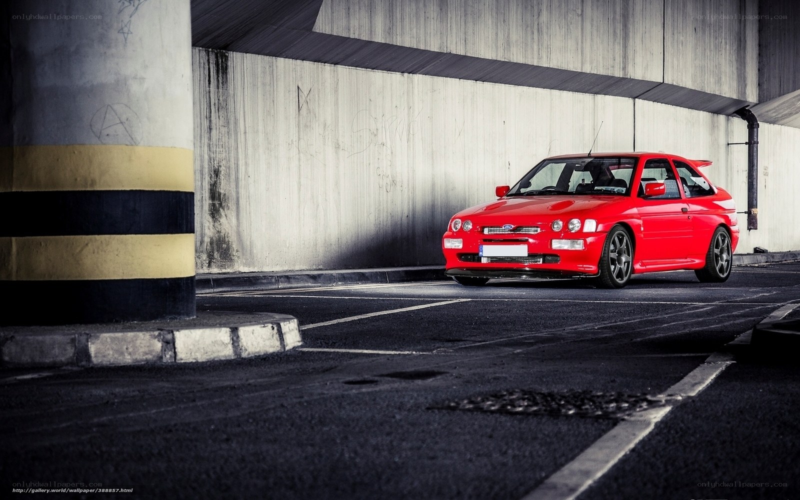 Red car under concrete overpass