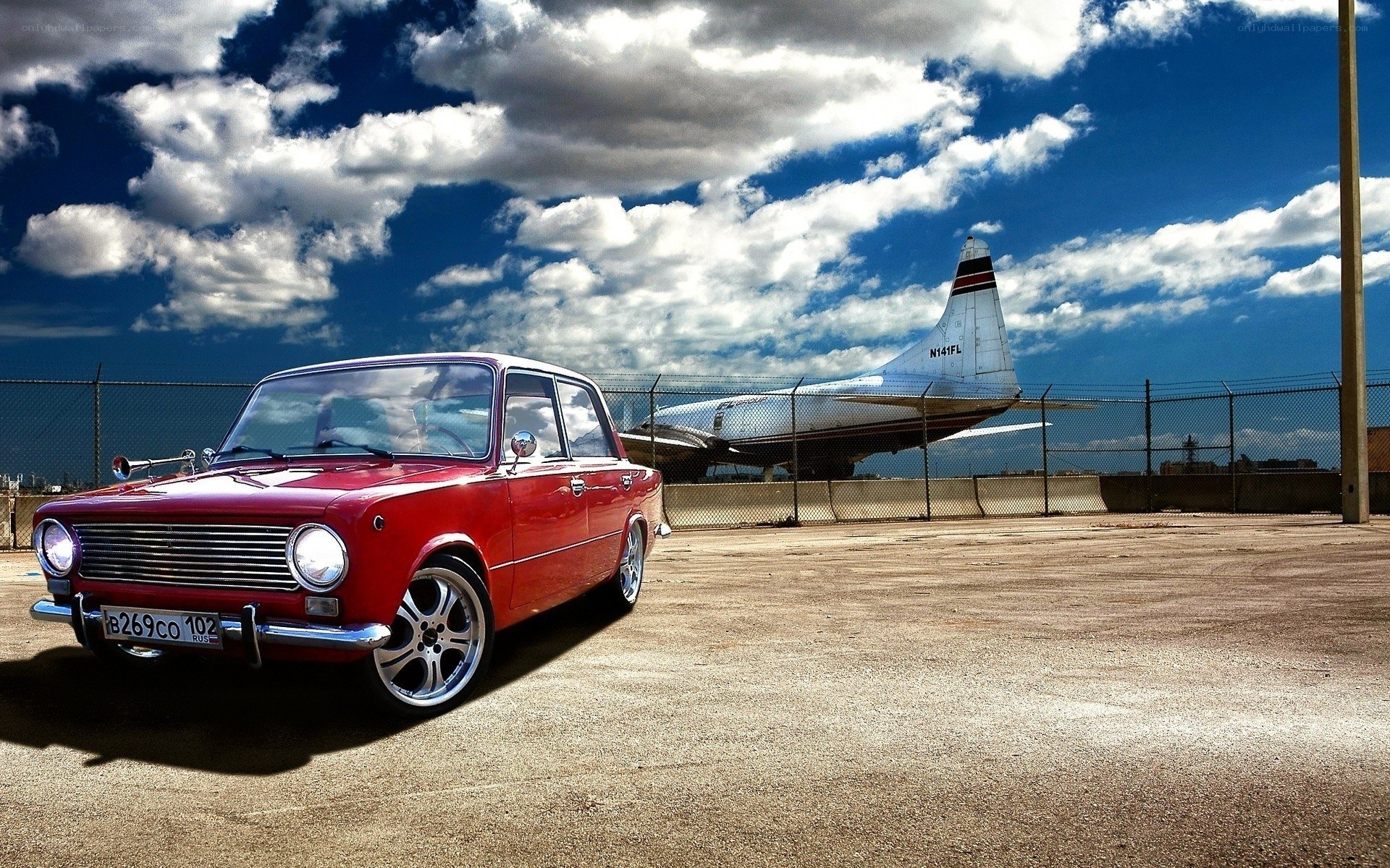 Red car with airplane in background