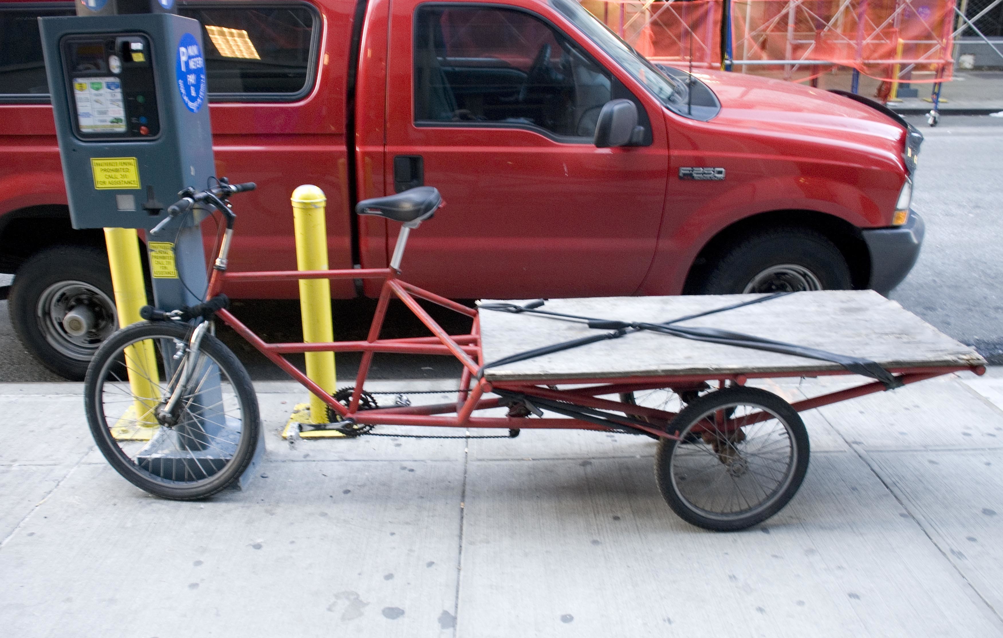 Red cargo bike parked on sidewalk