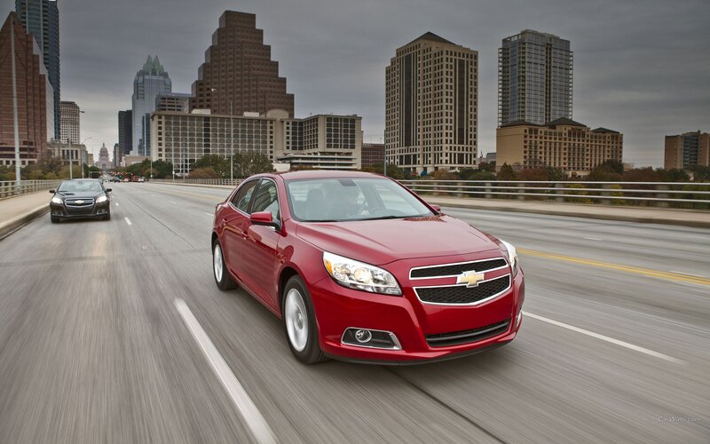 Red Chevrolet Malibu on city bridge