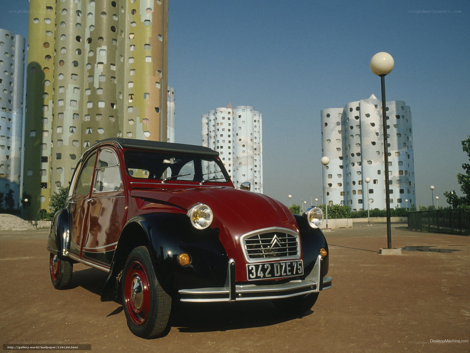 Red Citroën 2CV in front of modern buildings