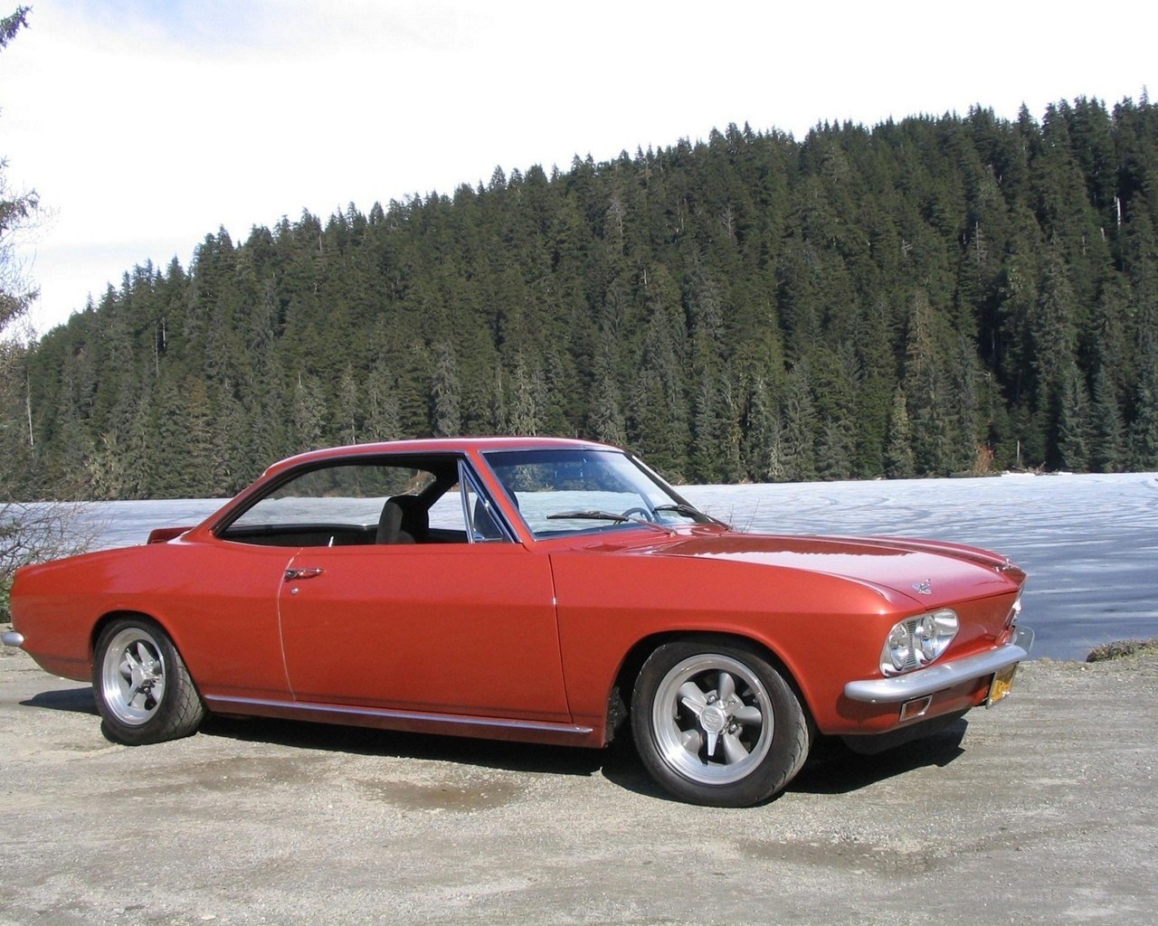 Red classic car by a lake