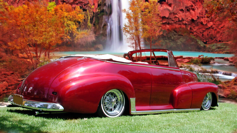 Red classic car by waterfall