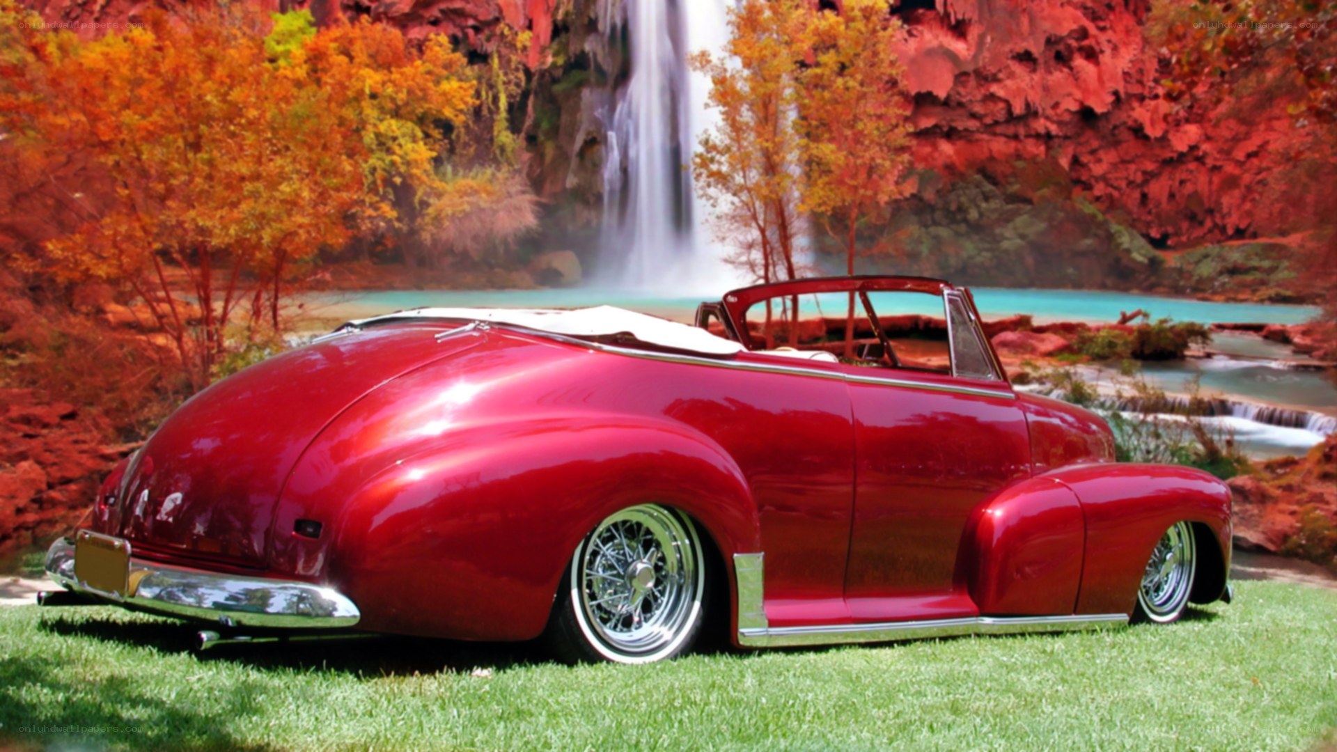 Red classic car by waterfall