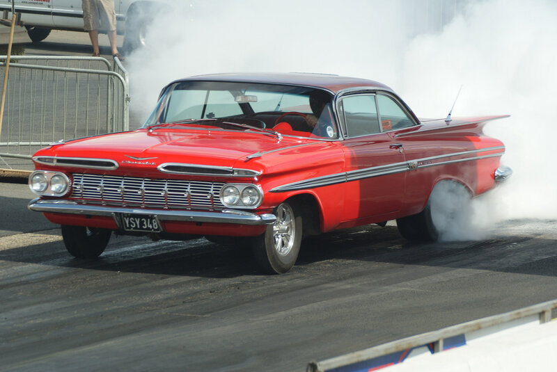 Red classic car doing burnout