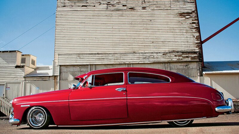 Red classic car in front of old building