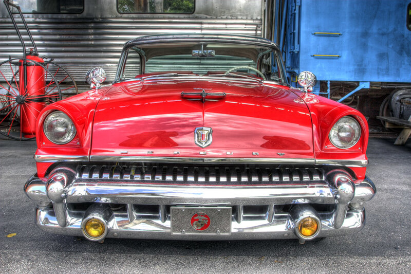 Red classic car in front of train