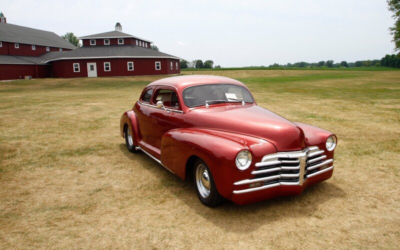 Red classic car on a farm field