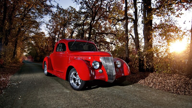 Red classic car on a forest road