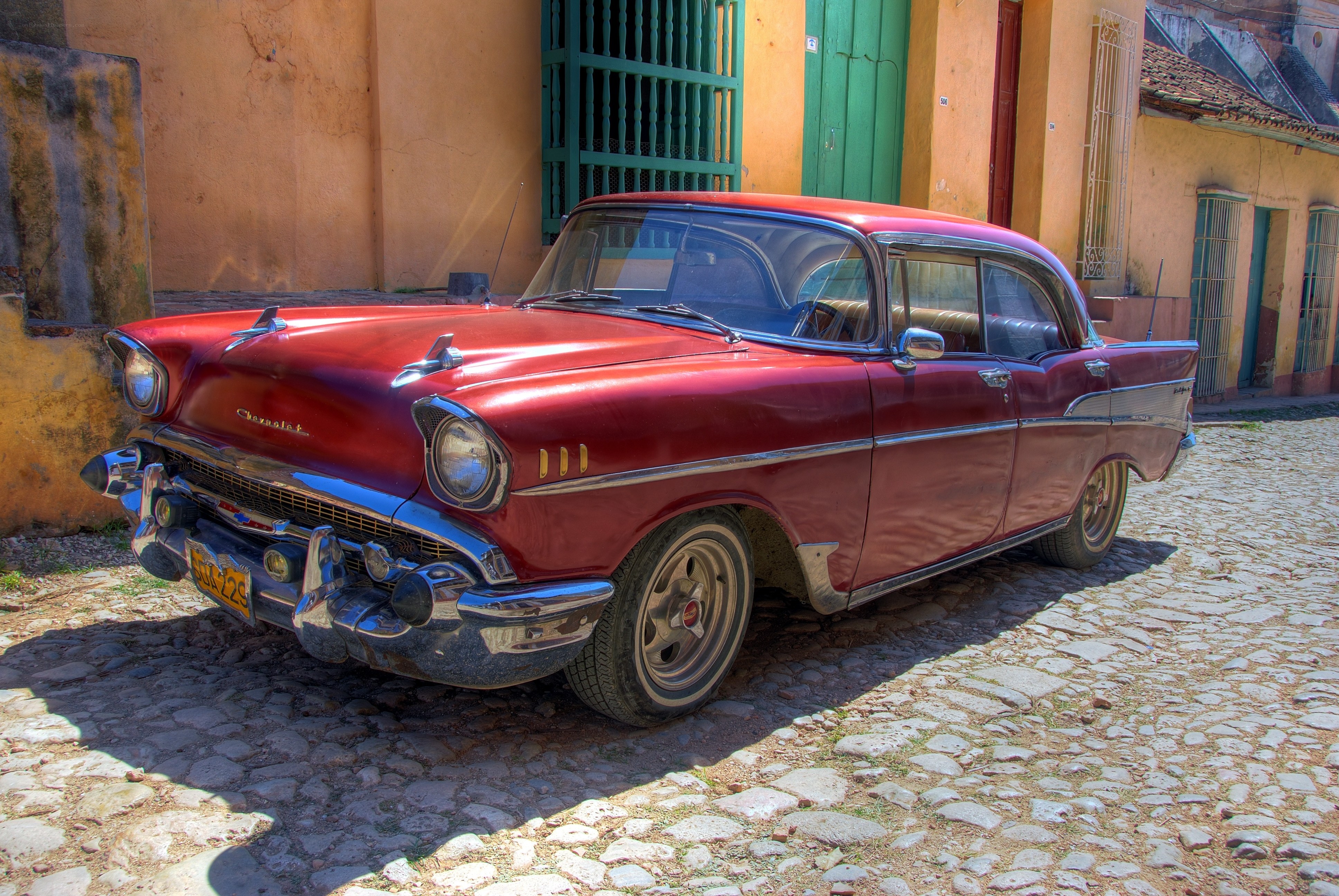 Red classic car on cobblestone street