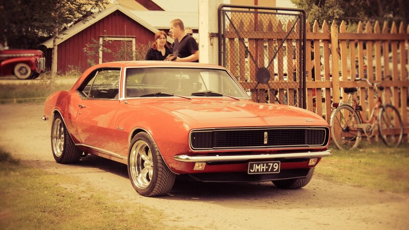 Red classic muscle car at a gathering