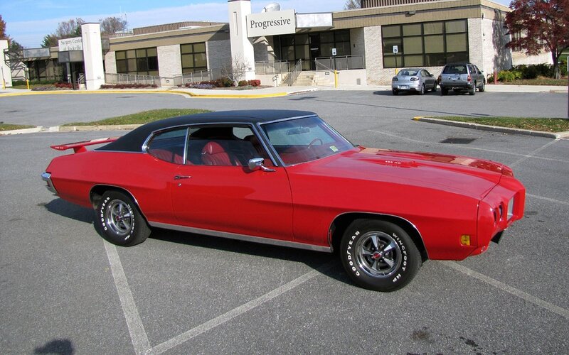 Red classic muscle car in parking lot