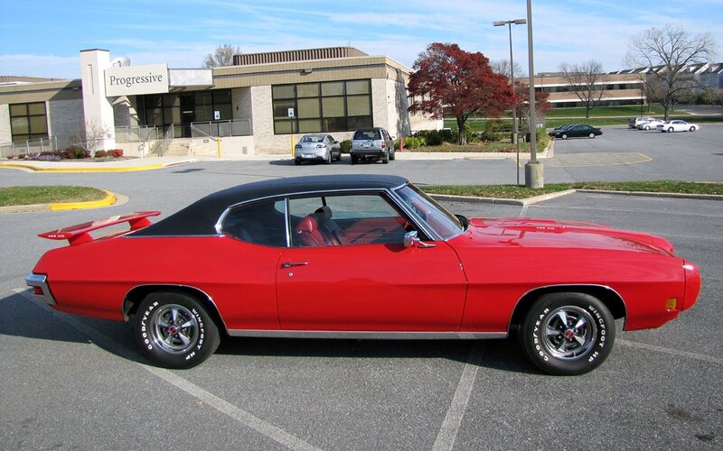 Red classic muscle car in parking lot
