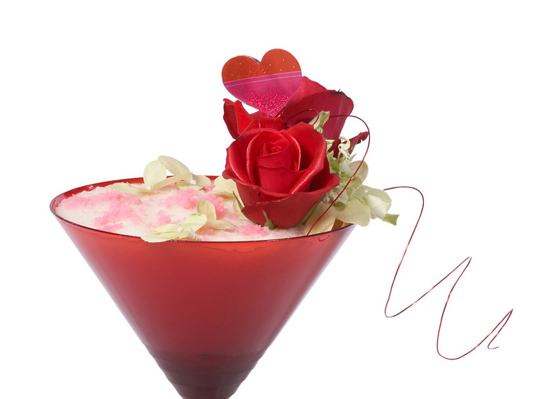 Red cocktail with rose garnish