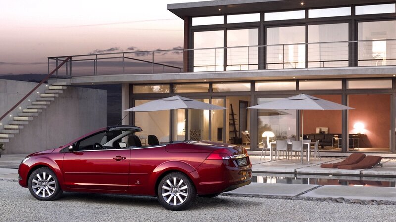 Red convertible by modern house