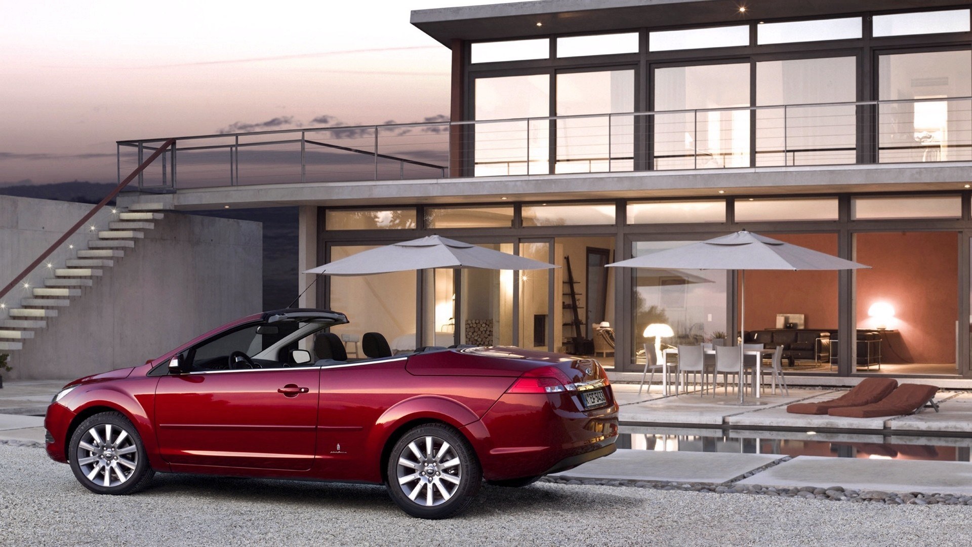Red convertible by modern house