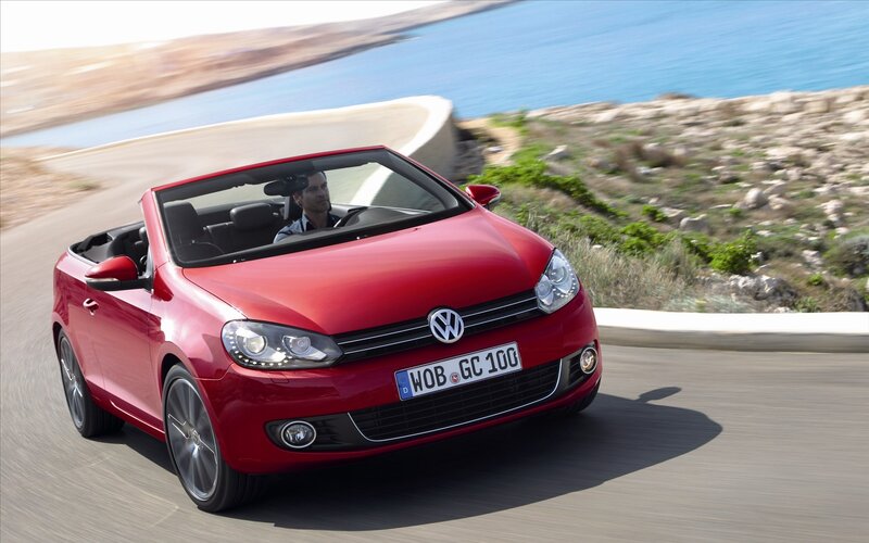 Red convertible driving on coastal road