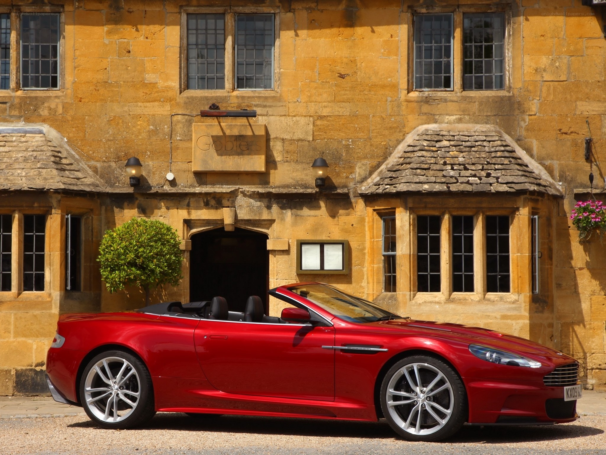 Red convertible in front of stone building