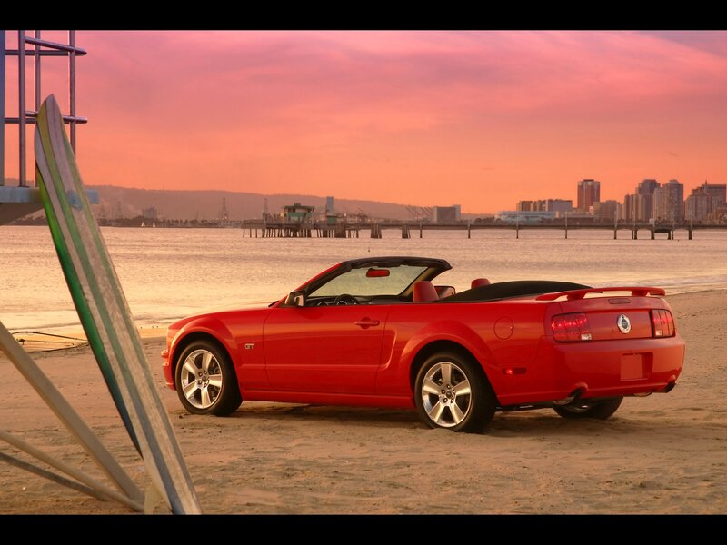 Red convertible on beach at sunset