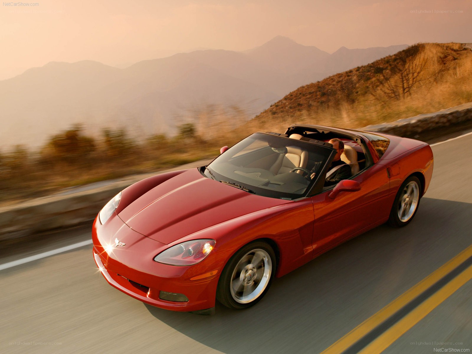 Red Corvette driving on mountain road