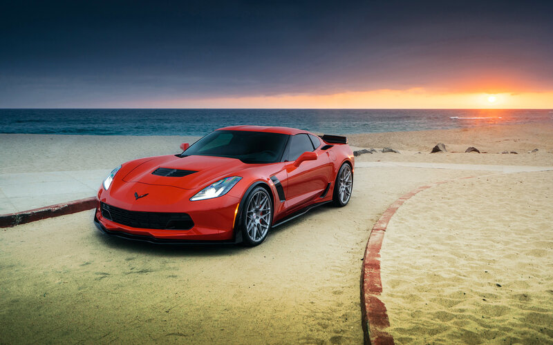 Red Corvette on beach at sunset