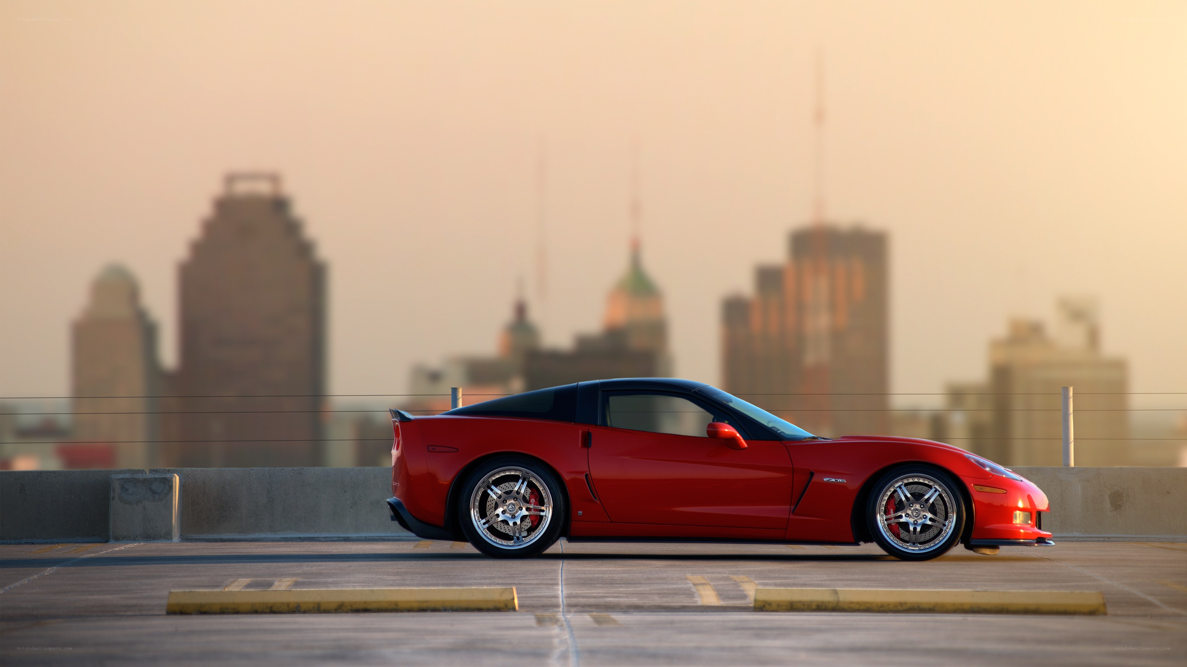 Red Corvette on rooftop with city skyline