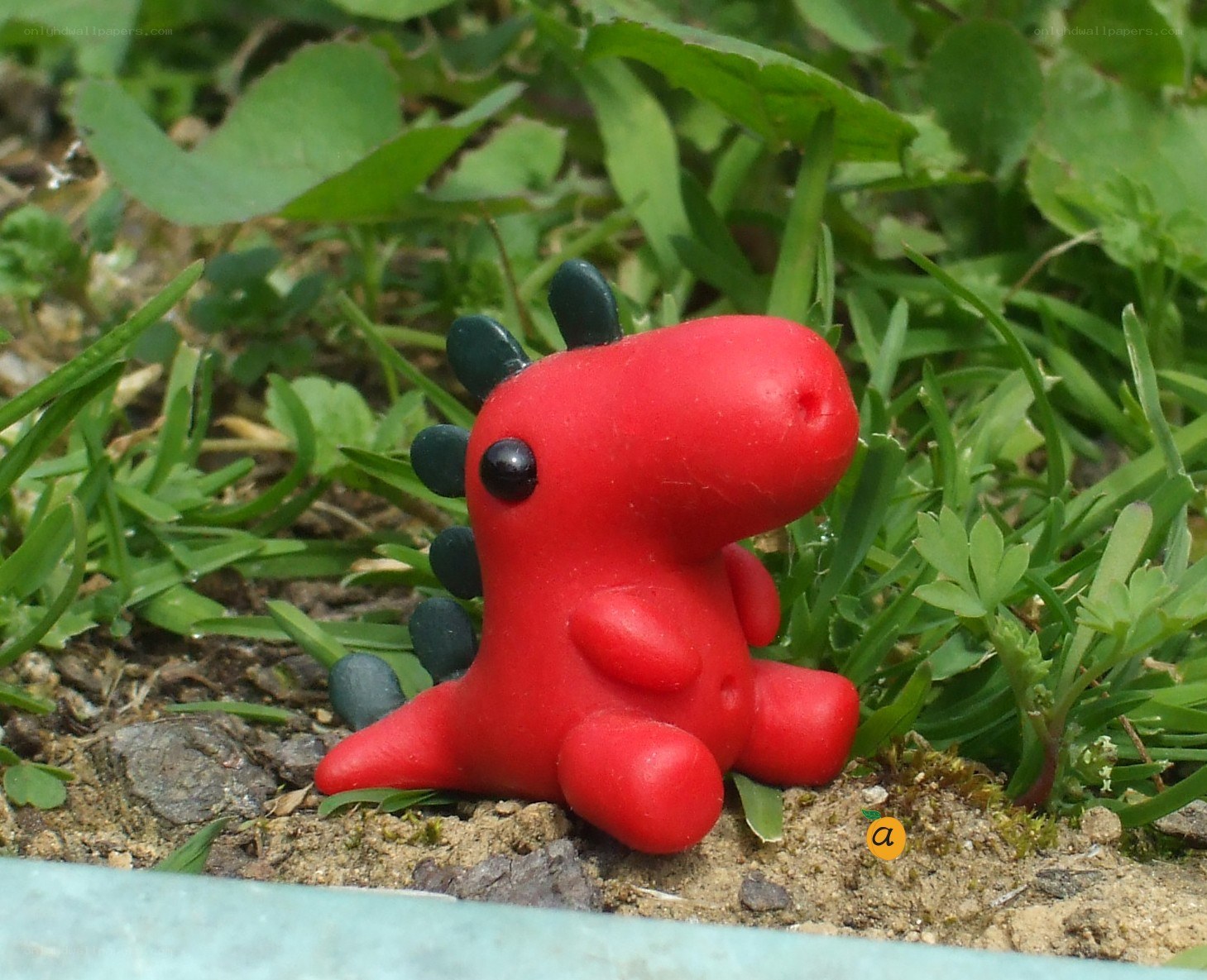 Red dinosaur figurine in grass